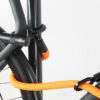 Bügelschloss mit Verlängerung aus orangenem Textil sichert drei Fahrrad-Komponenten gleichzeitig am Fahrradständer ab