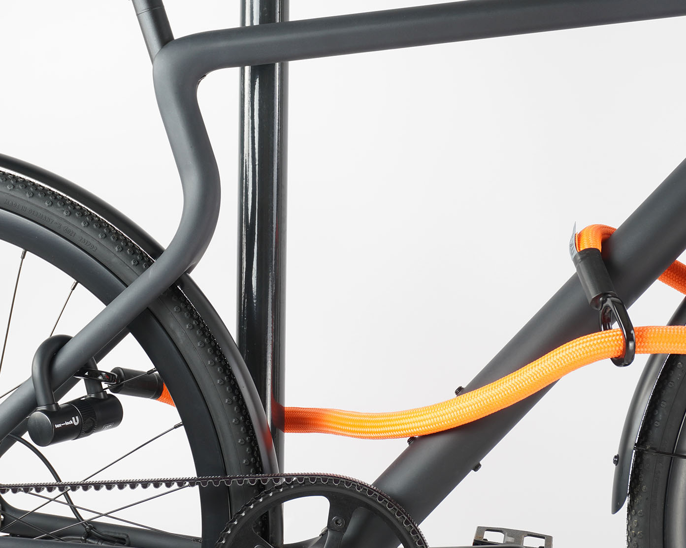 Bügelschloss mit Verlängerung aus Textil in orange sichert Vorder-, Hinterrad und Rahmen gleichzeitig am Fahrradständer ab