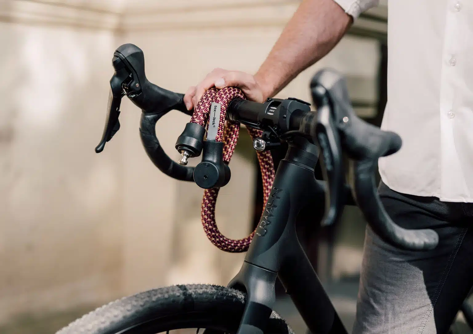 tex-lock orbit in chateau red dangles open over racing bike handlebars with male model in the background