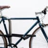Hinterrad und Oberrohr vom Fahrrad mit schwarzem Seilschloss aus Textil an Fahrradständer angeschlossen