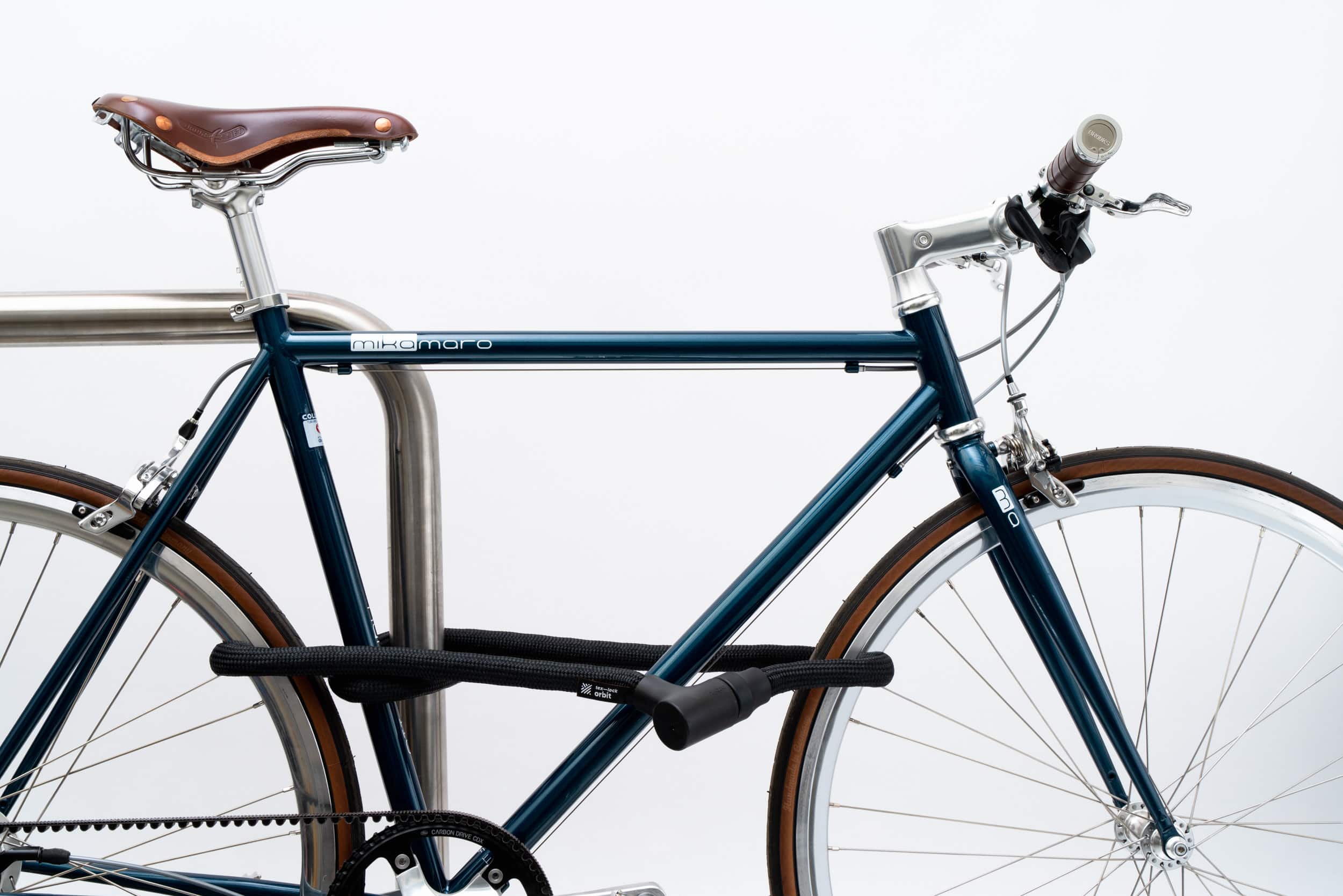 Hinterrad und Oberrohr vom Fahrrad mit schwarzem Seilschloss aus Textil an Fahrradständer angeschlossen
